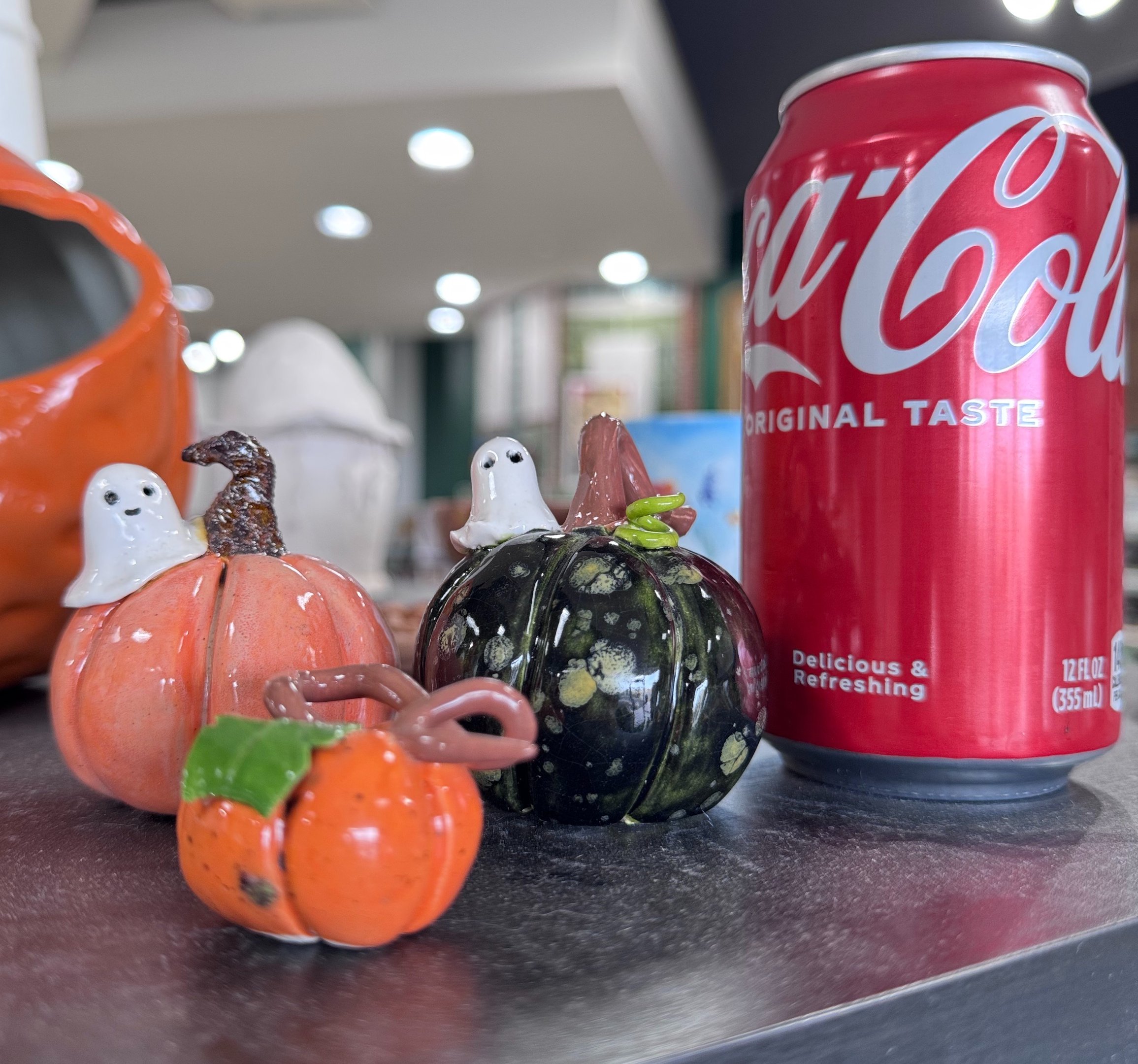 Three cute ceramic pumpkins next to a soda can for size reference